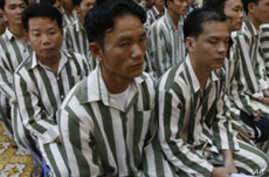 Vietnamese men in black and white vertically striped prison uniforms.]