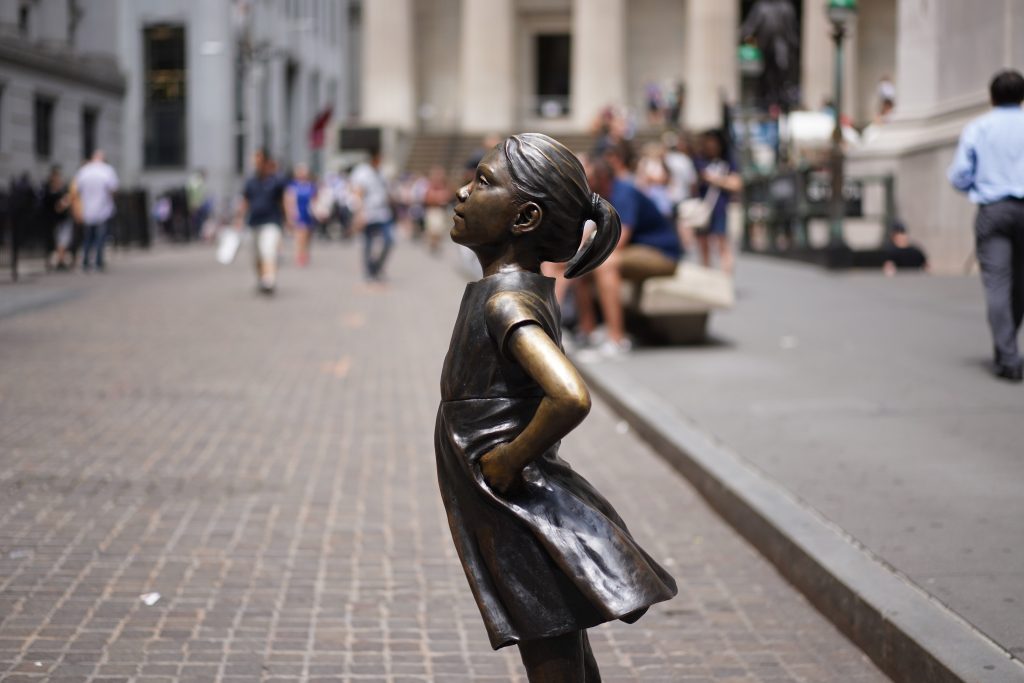 A bronze sculpture of a little girl at an intersection. “Fearless Girl” statue in New York