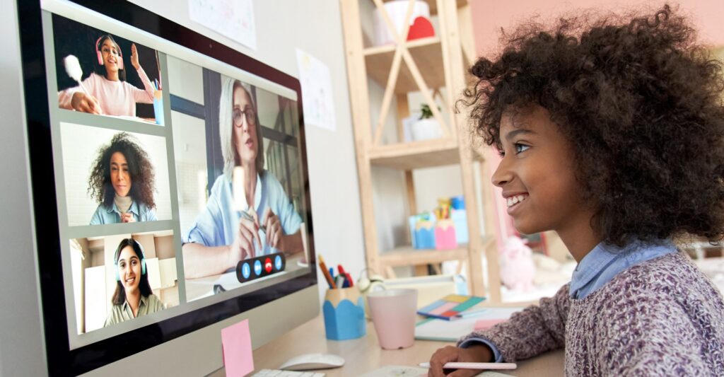 A youth smiles at a videoconference on a desktop computer