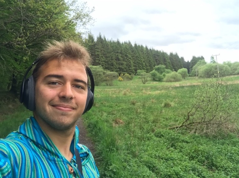 CCL intern André wearing headphones in the middle of a green field
