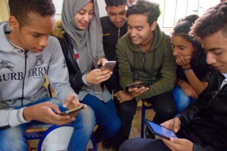 A group of students looking at their phones and tablets.